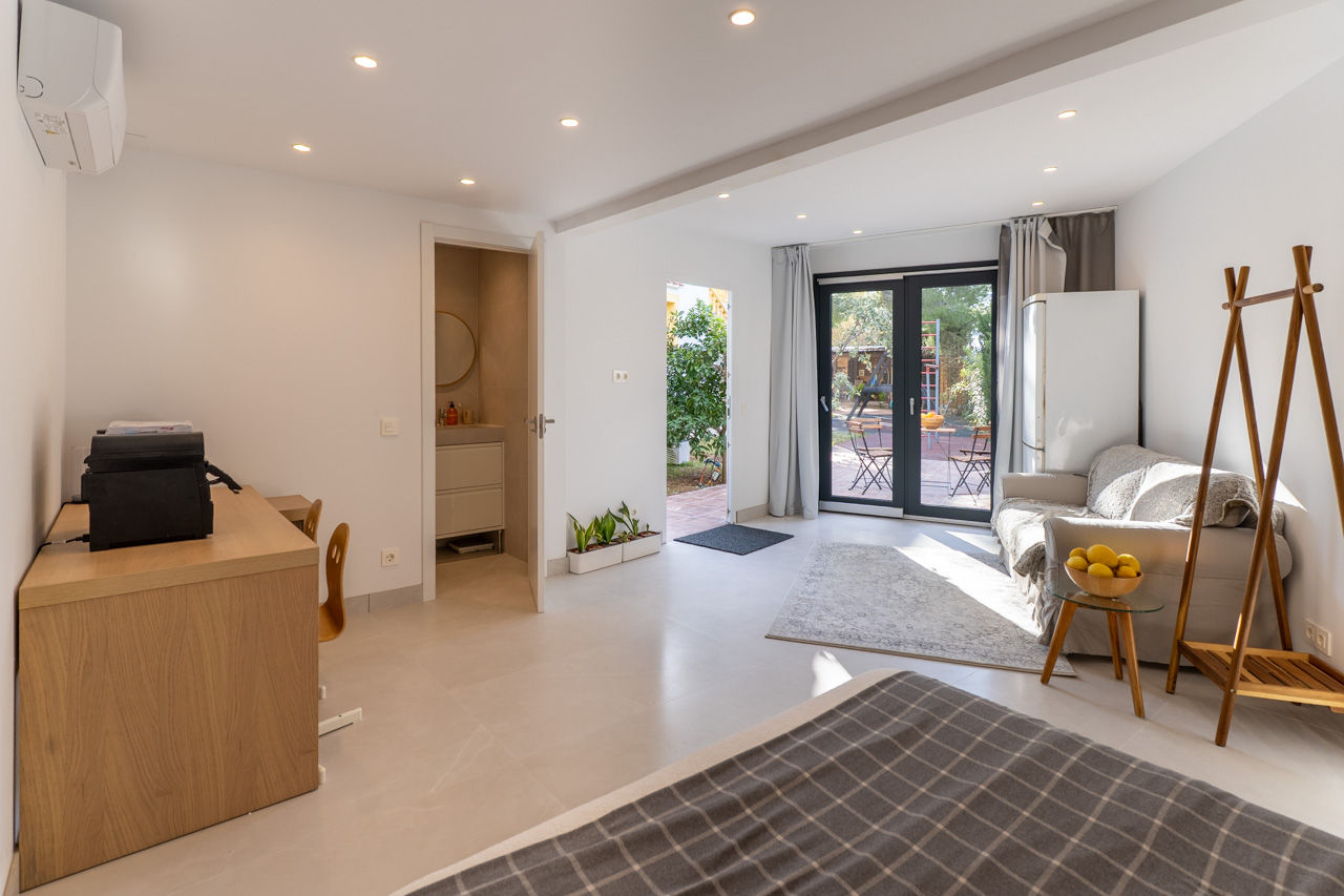 Lichte, multifunctionele ruimte met toegang tot de tuin, en-suite badkamer en functioneel meubilair in neutrale tinten.