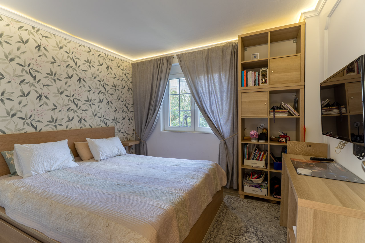 Lichte slaapkamer met bloemenbehang, een licht houten bedframe en bijpassende modulaire rekken.