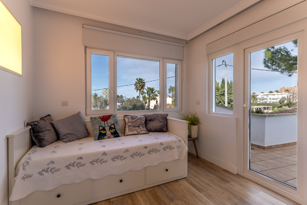 Lichte slaapkamer met daybed, uitzicht naar buiten en toegang tot terras.
