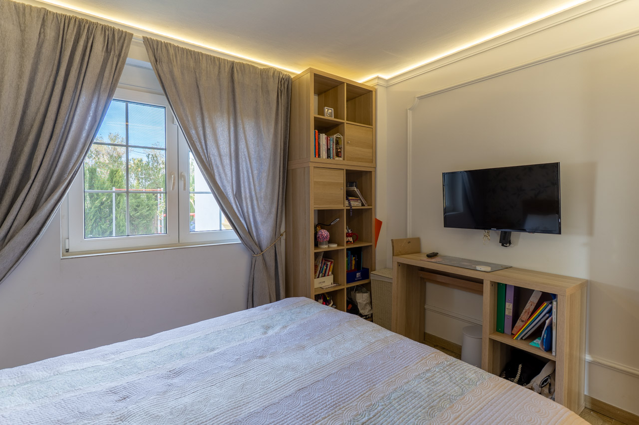 Lichte slaapkamer met lichte houten stellingkasten en grijze gordijnen naast een raam.