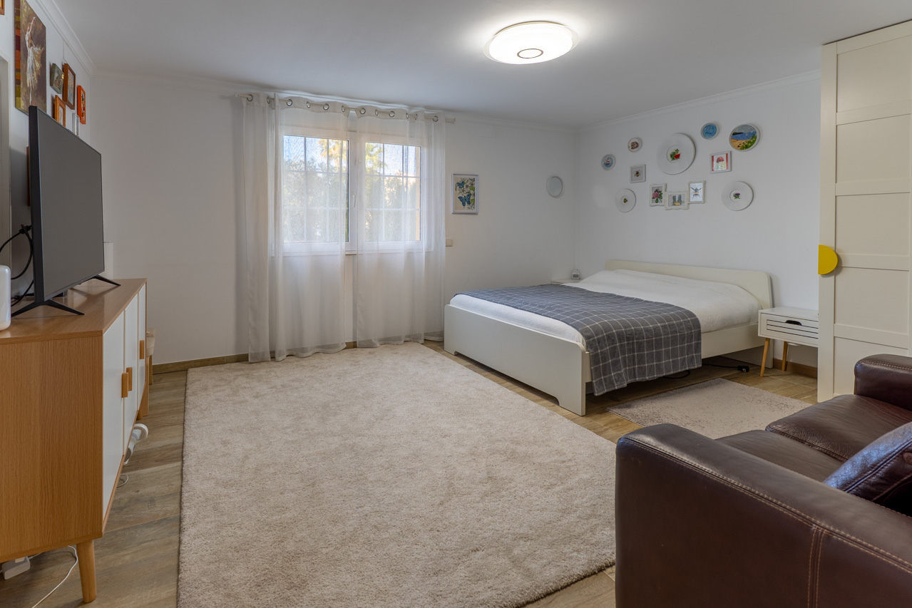 Lichte slaapkamer met wit bed, zacht vloerkleed en decoratieve kunst aan de muur.