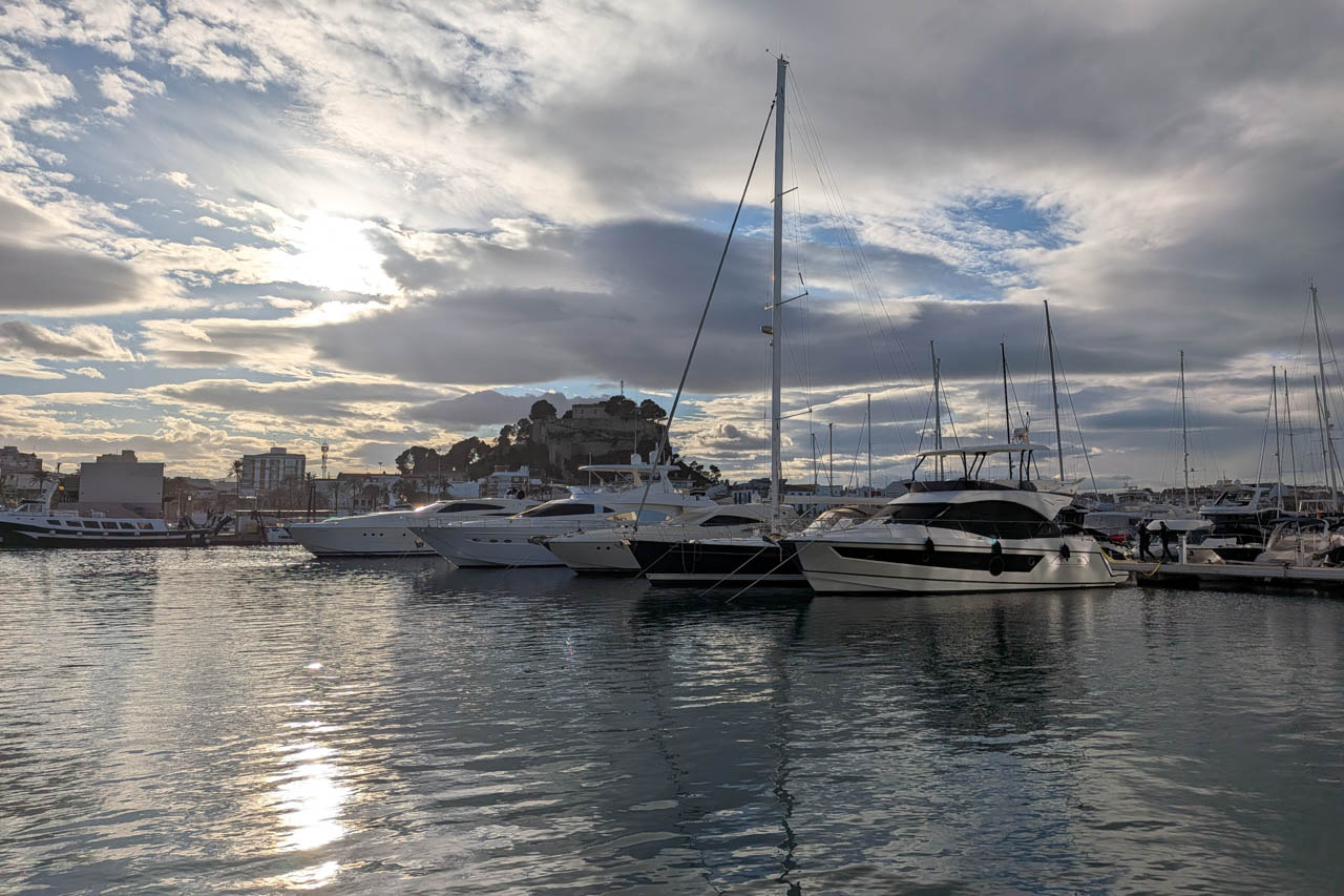 Marina met jachten en zonreflecties op het water.