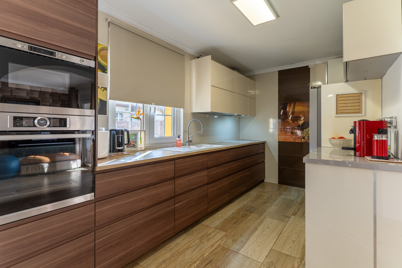 Moderne keuken met houten kasten, licht aanrechtblad en tegels met houtlook.