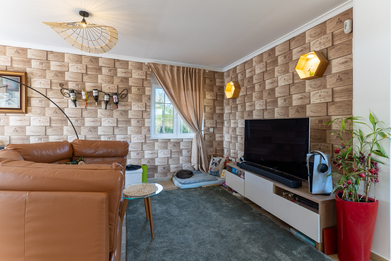 Woonkamer met behang in wijnkistmotief en een bruine leren bank.