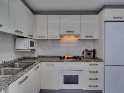 Functionele keuken met granieten aanrechtblad, witte apparaten en warme verlichting.