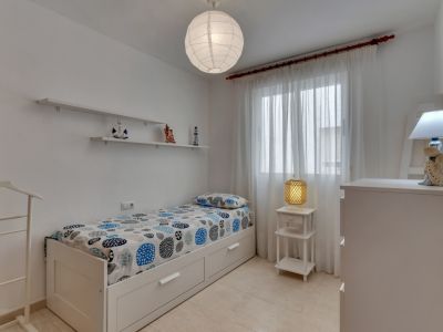 Lichte slaapkamer met eenpersoonsbed, decoratieve planken en nautische accenten.