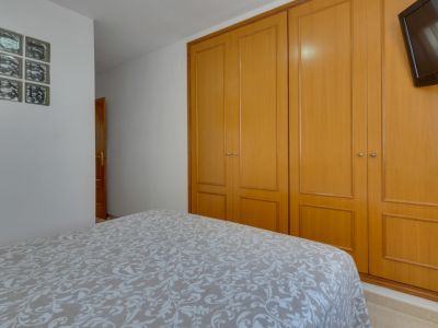 Lichte slaapkamer met tweepersoonsbed en ingebouwde houten kledingkast. Functionele, minimalistische inrichting.