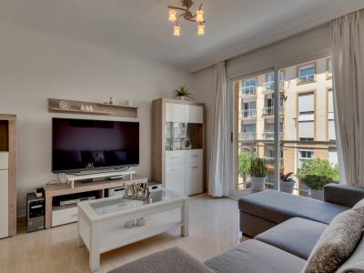 Lichte woonkamer met modern meubilair en toegang tot balkon met uitzicht op de stad.