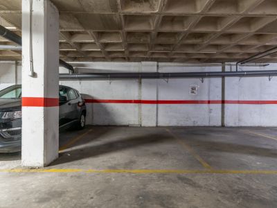 Ondergrondse parkeerplaats met betonnen vloer en cassetteplafond.
