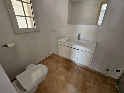 Toilet met modern wastafelmeubel en crèmekleurige tegelvloer.