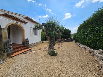 Villa-ingang met grind, terracotta treden en zandstenen boog.