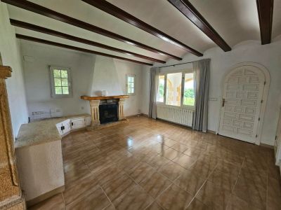 Woonkamer met stenen open haard, houten balken en tegelvloer.