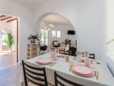 Lichte eetkamer met een tafel gedekt in roze en gouden tinten, met toegang tot het terras en de woonkamer.
