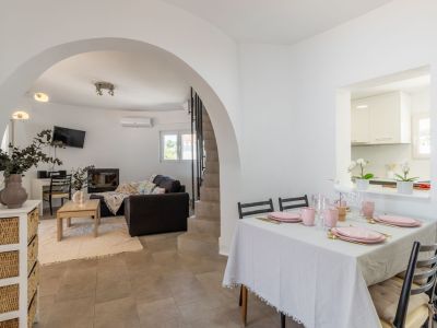 Lichte eetkamer met gedekte tafel in roze tinten en toegang tot de gewelfde woonkamer.