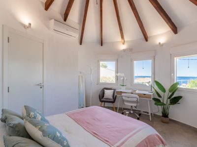 Lichte slaapkamer met gewelfd plafond met houten balken en een bureau met uitzicht op zee.