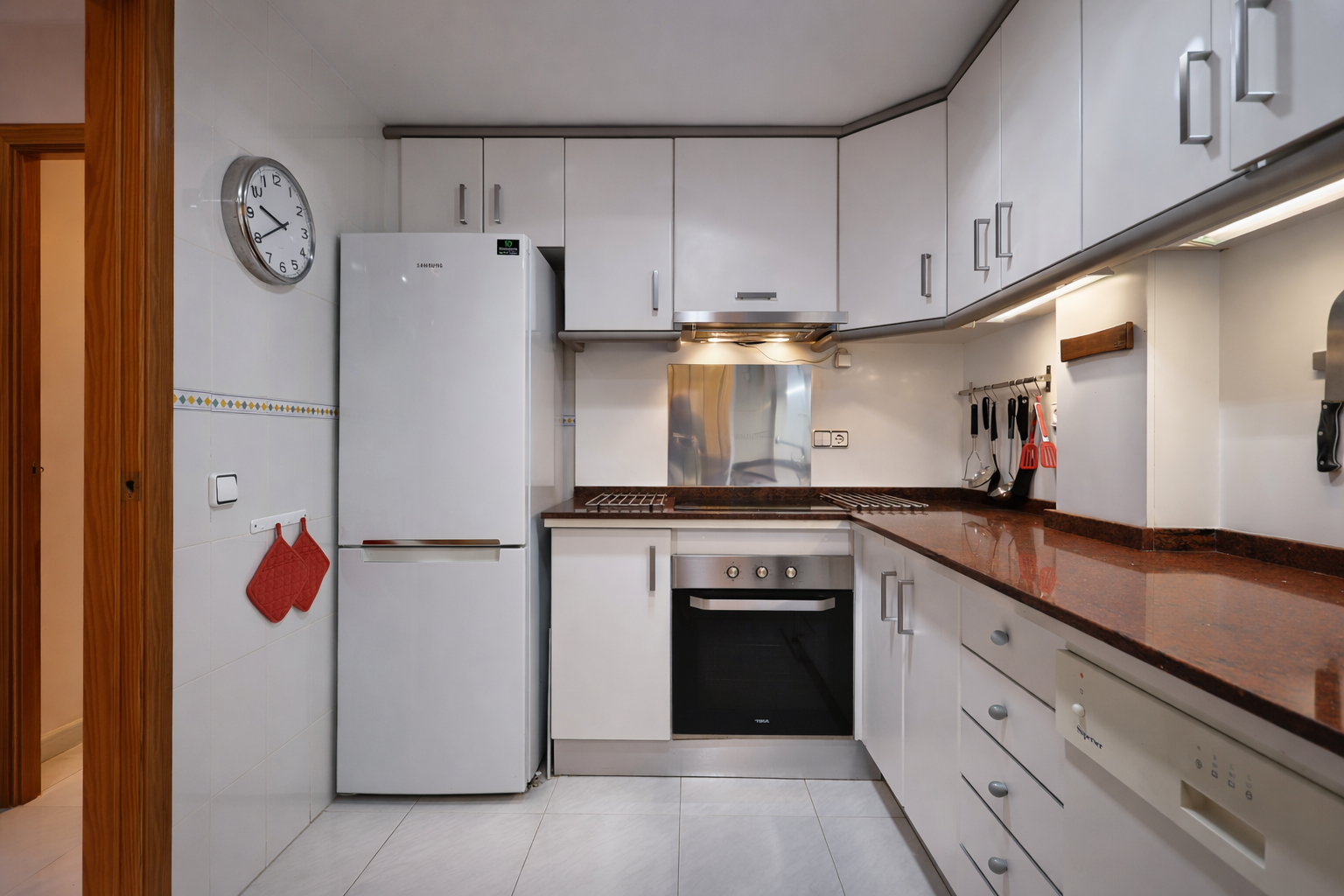 Functionele keuken met granieten aanrechtblad, witte apparaten en bovenkasten.