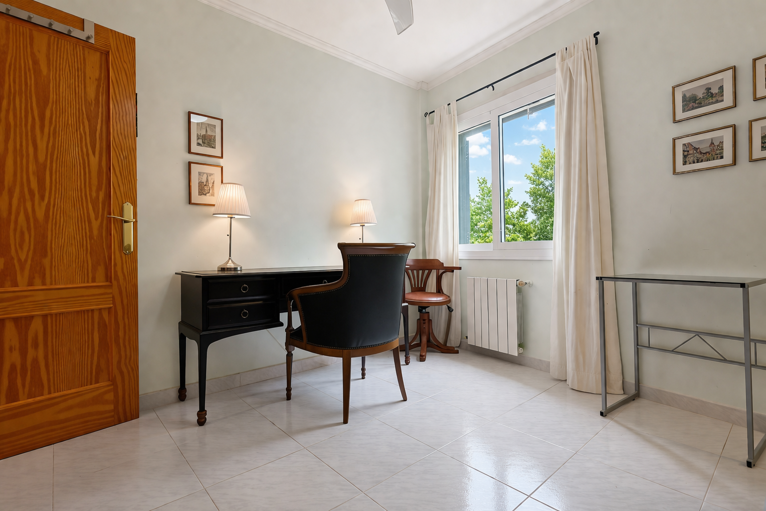 Lichte kamer met een klassiek donkerhouten bureau en gestoffeerde stoel, ideaal voor een studeer- of werkruimte.