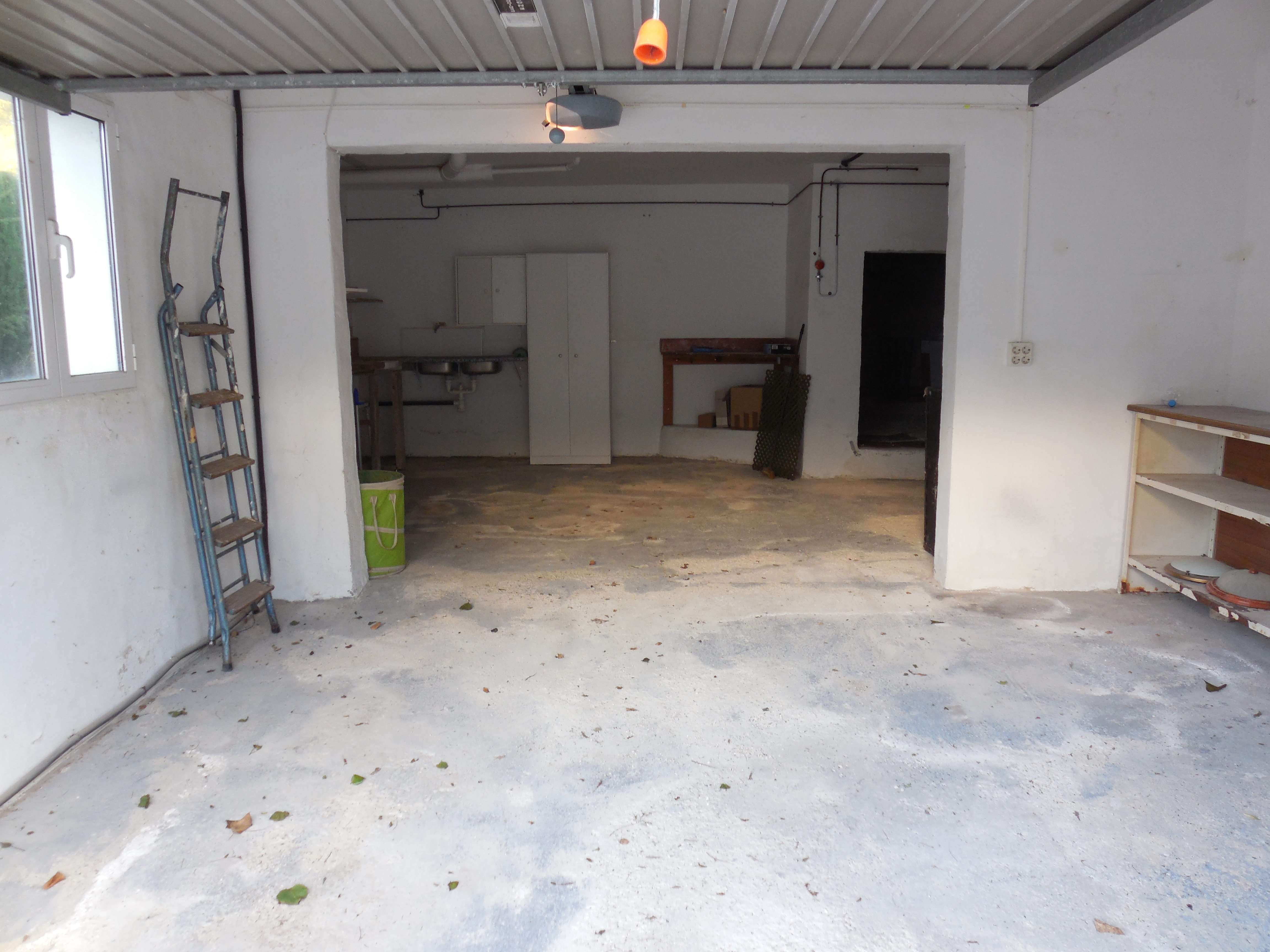 Garage met betonnen vloer, witte muren en metalen rekken.