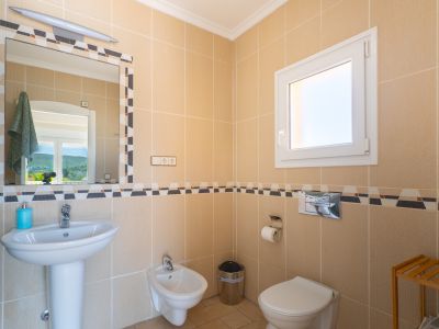 Badkamerdetail met crèmekleurige tegels en decoratieve rand. Inclusief wastafel, bidet en toilet.