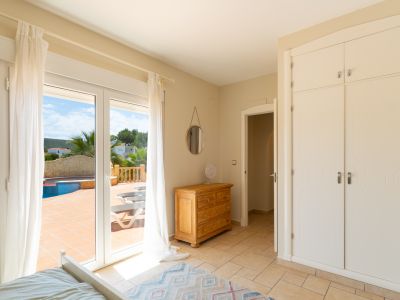 Lichte slaapkamer met toegang tot terras en uitzicht op het zwembad. Inclusief inbouwkast en houten dressoir.