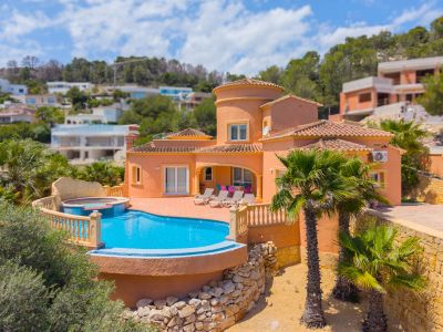 Luchtfoto van de villa met turquoise zwembad en geïntegreerde jacuzzi, omgeven door palmbomen en tuinen.