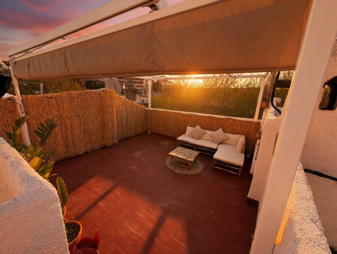Privéterras met luifel, rode tegelvloer en bamboe omheining. Voorzien van tuinmeubilair en uitzicht op de zonsondergang.