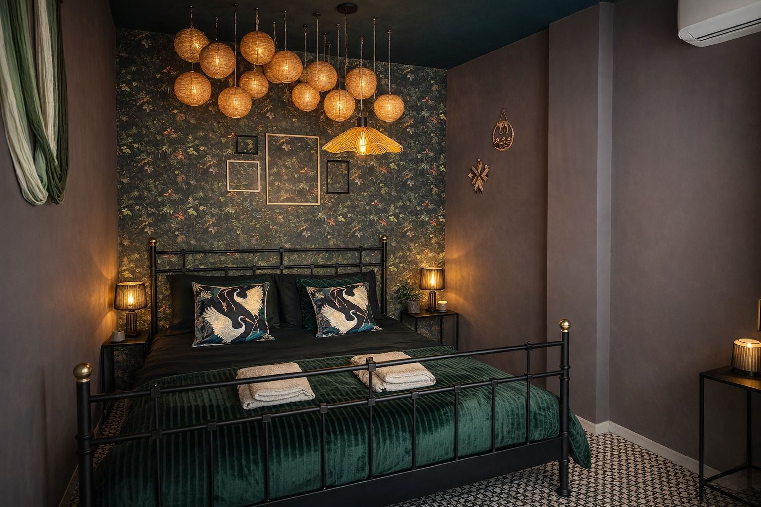 Slaapkamer met bloemenbehang, smeedijzeren bed, groene fluwelen sprei en bedlampjes.