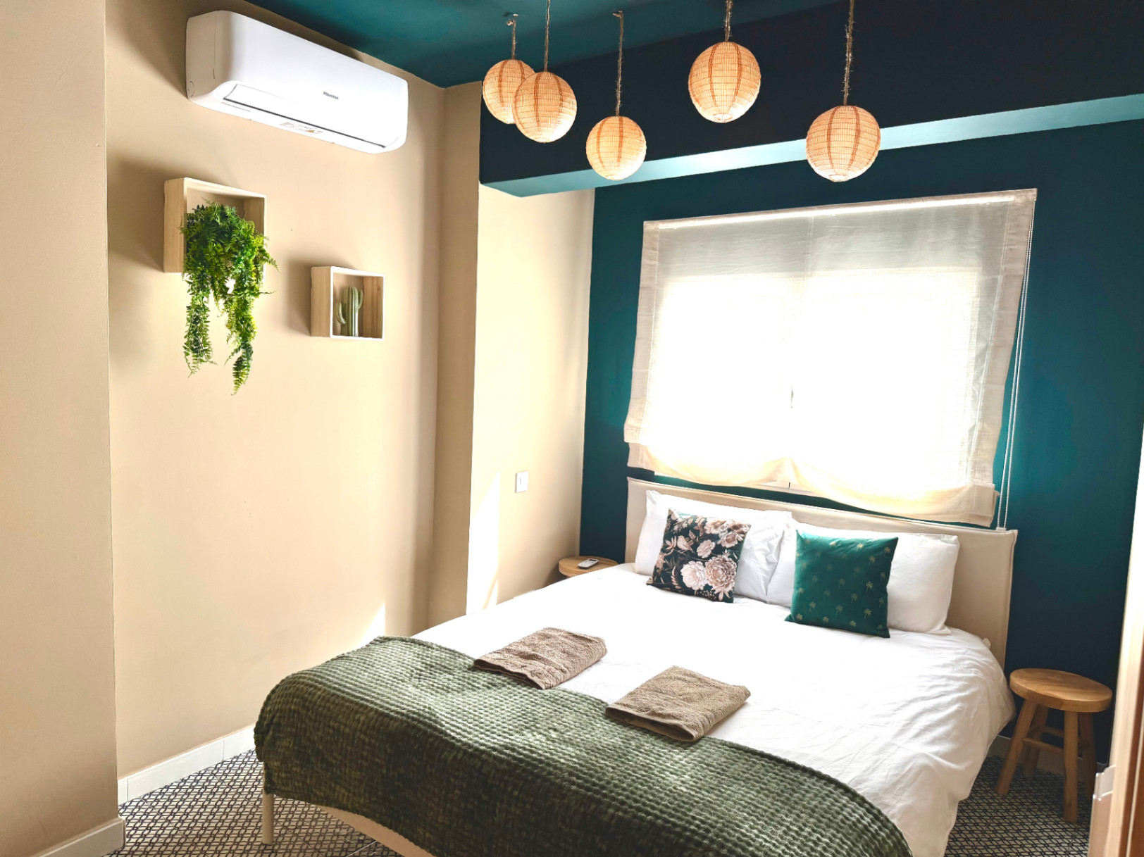 Slaapkamer met crèmekleurige muren en blauwgroene accenten. Hanglampen en minimalistische inrichting.