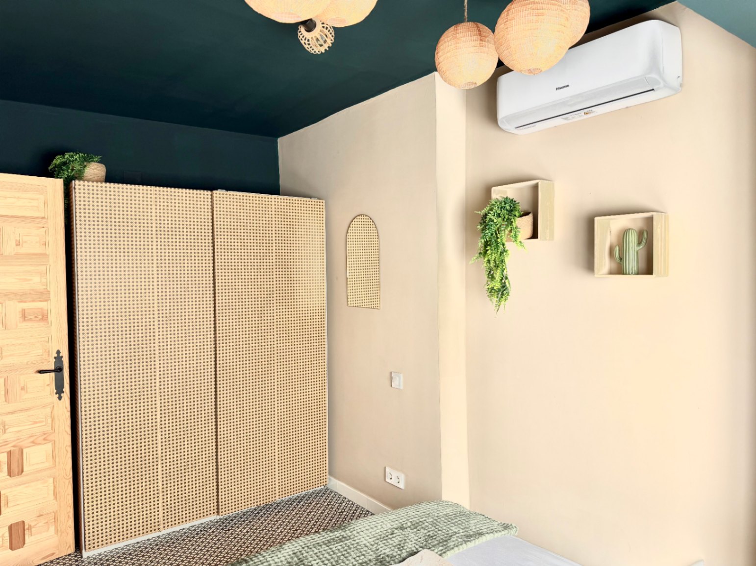 Slaapkamer met rotan kledingkast, donkergroen plafond en minimalistische wanddecoratie.