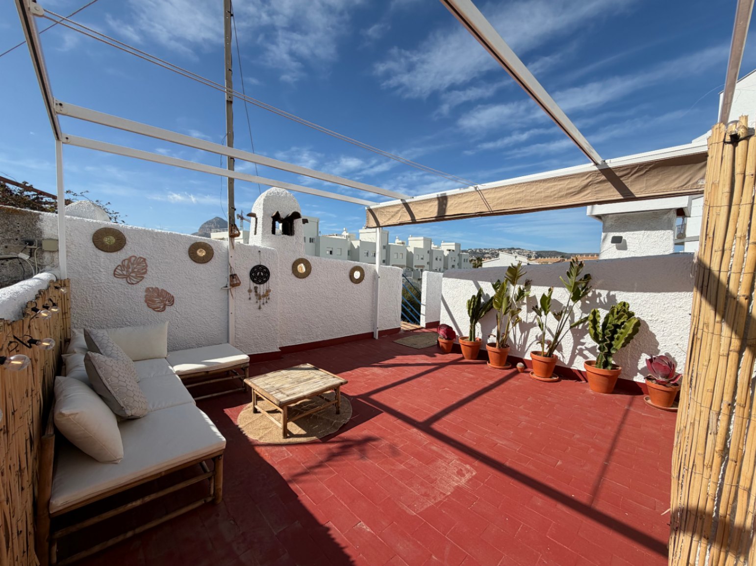 Terras met terracotta vloer, bamboe meubilair en handgemaakte wanddecoraties.