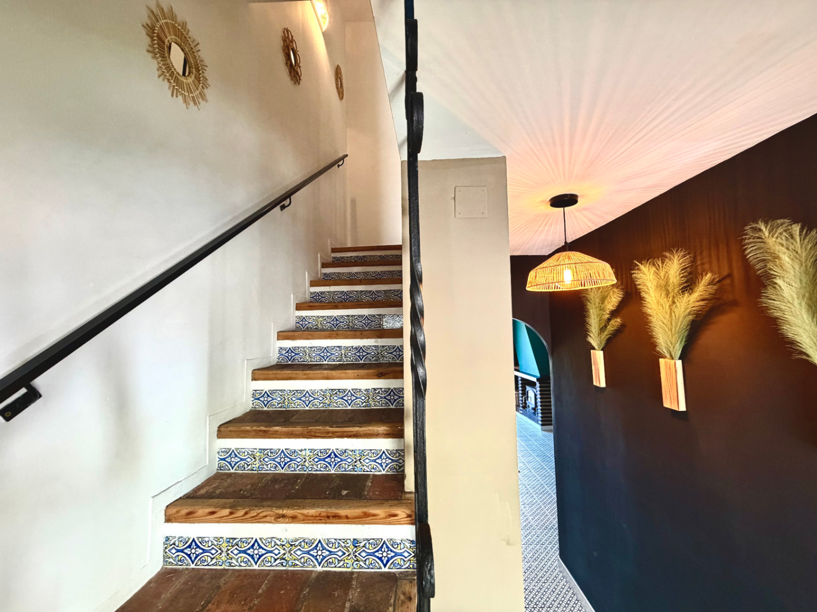 Trapdetail met decoratieve tegels, muur met spiegels en design wandlampen.
