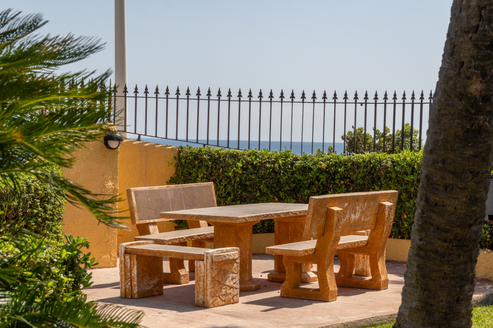 Buitenzithoek met stenen tafel en banken, mediterrane tuinen en uitzicht op zee.