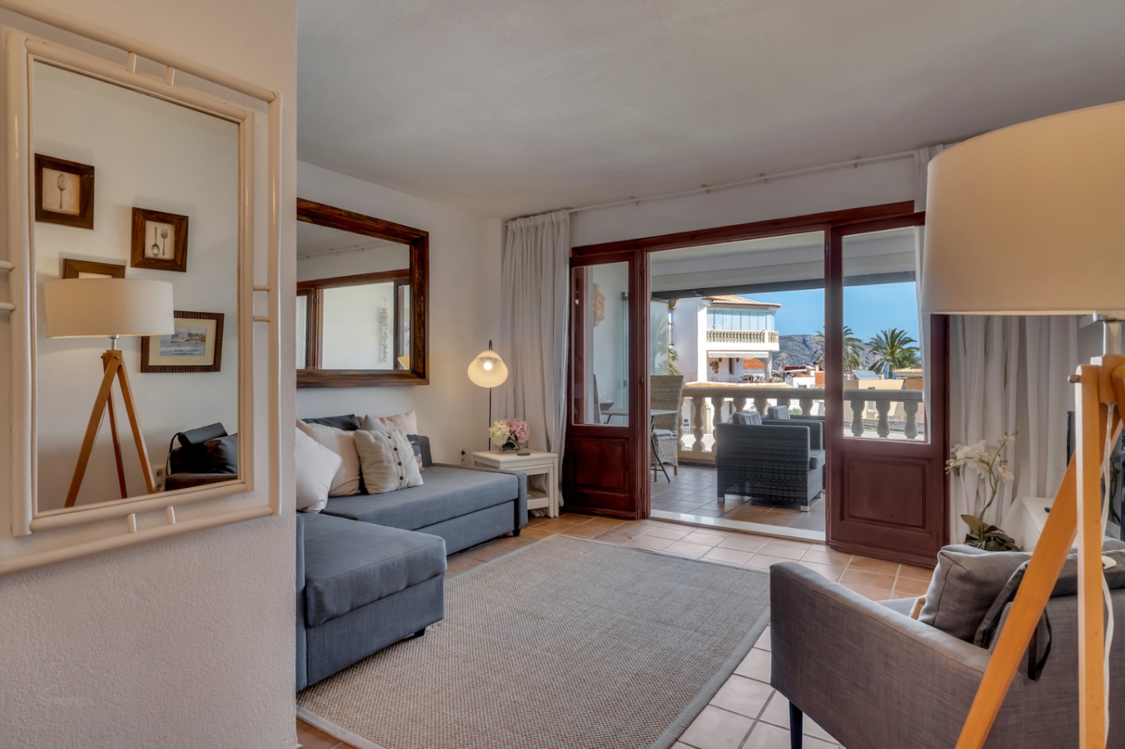 Lichte woonkamer met glazen terras en uitzicht op zee in Jávea. Grijze bank en moderne inrichting.
