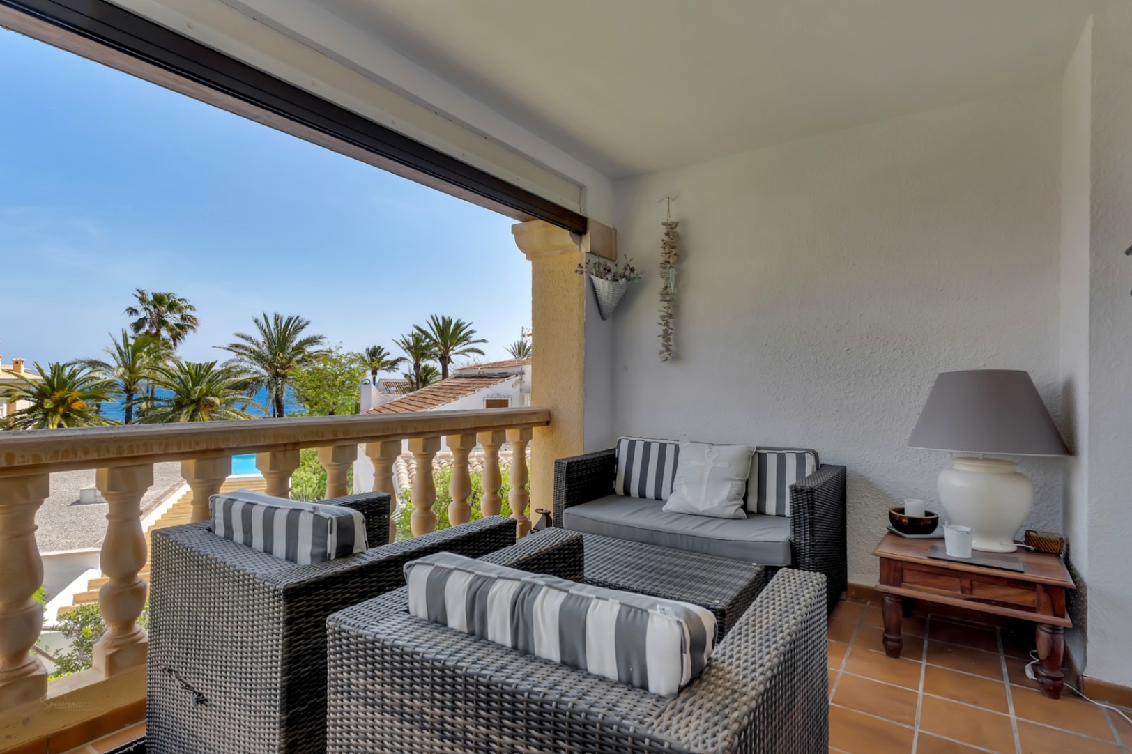 Terras met zeezicht, ingericht met rieten fauteuils en gestreepte kussens, ideaal om te ontspannen.