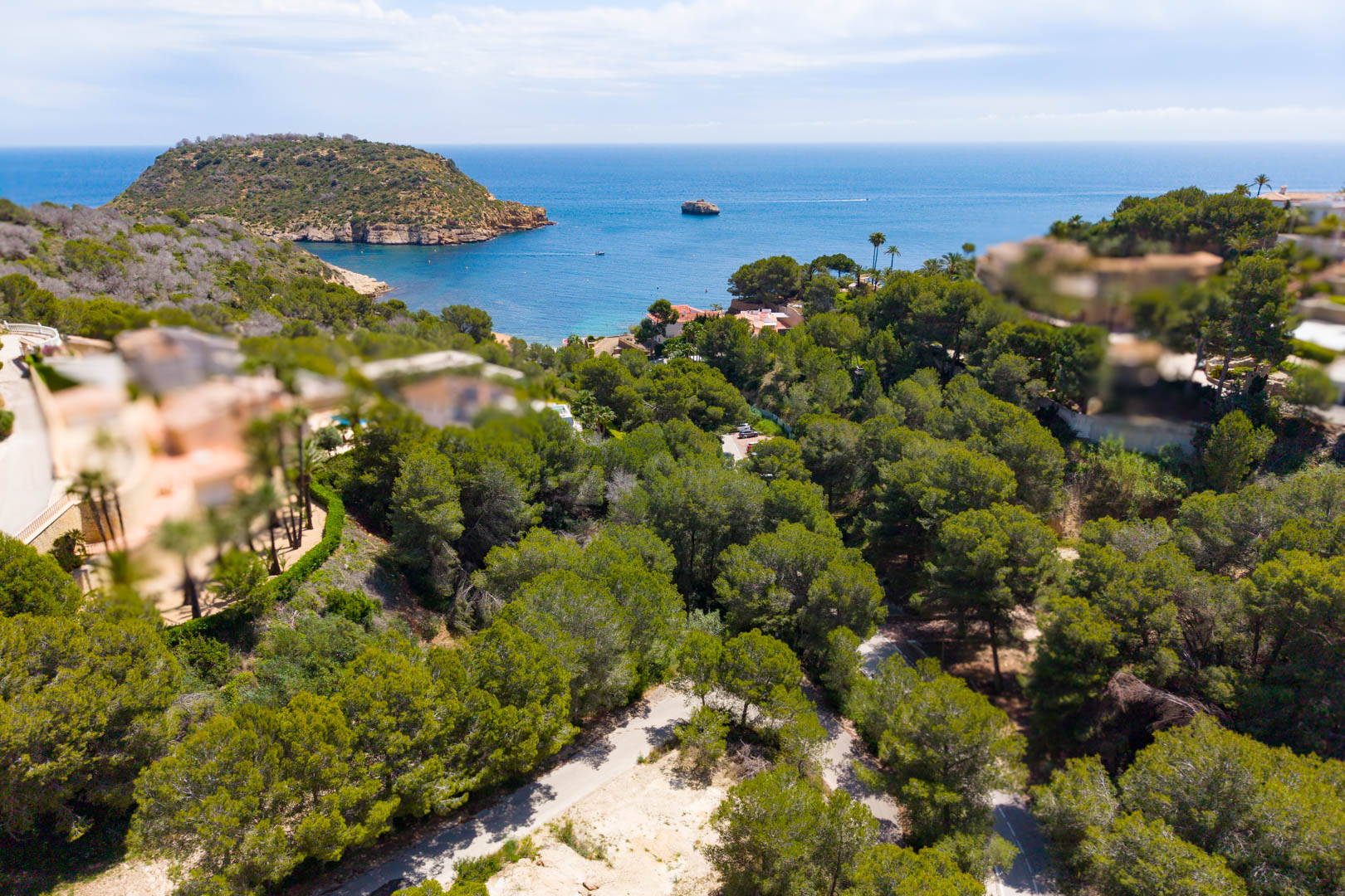 Luchtfoto van het beboste perceel met toegangsweg, met uitzicht op de zee en de landtong in Jávea.
