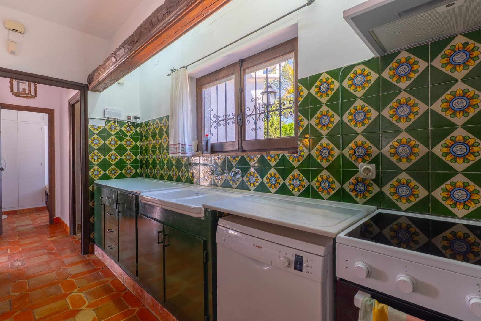 Rustieke keuken met decoratieve tegels, marmeren aanrechtblad en terracotta vloer.