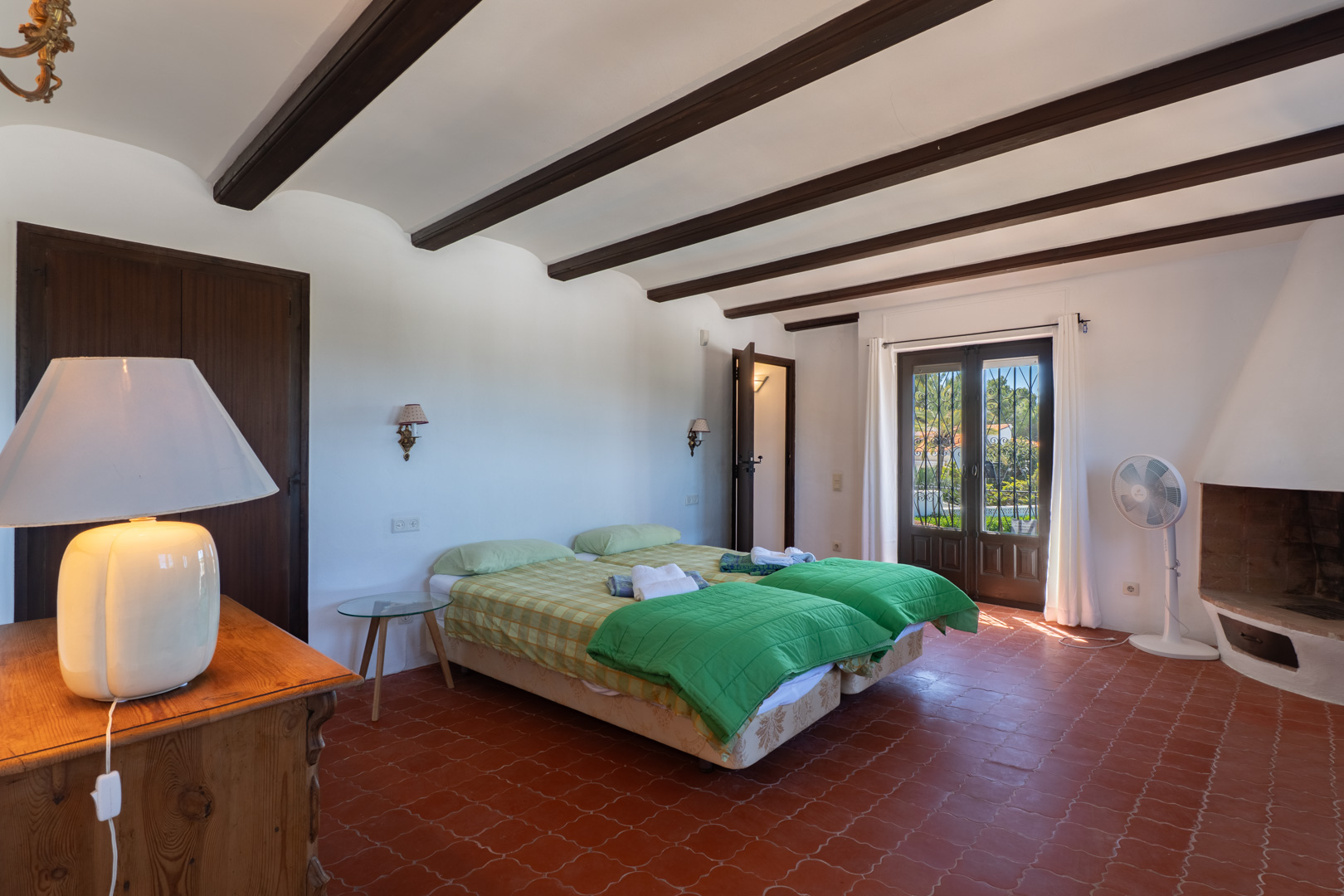 Slaapkamer met twee eenpersoonsbedden, houten balken en terracotta vloertegels.