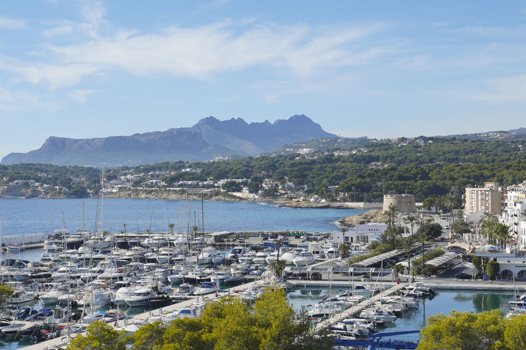 Uitzicht op de jachthaven van Moraira met op de achtergrond de beboste kustlijn en bergen.