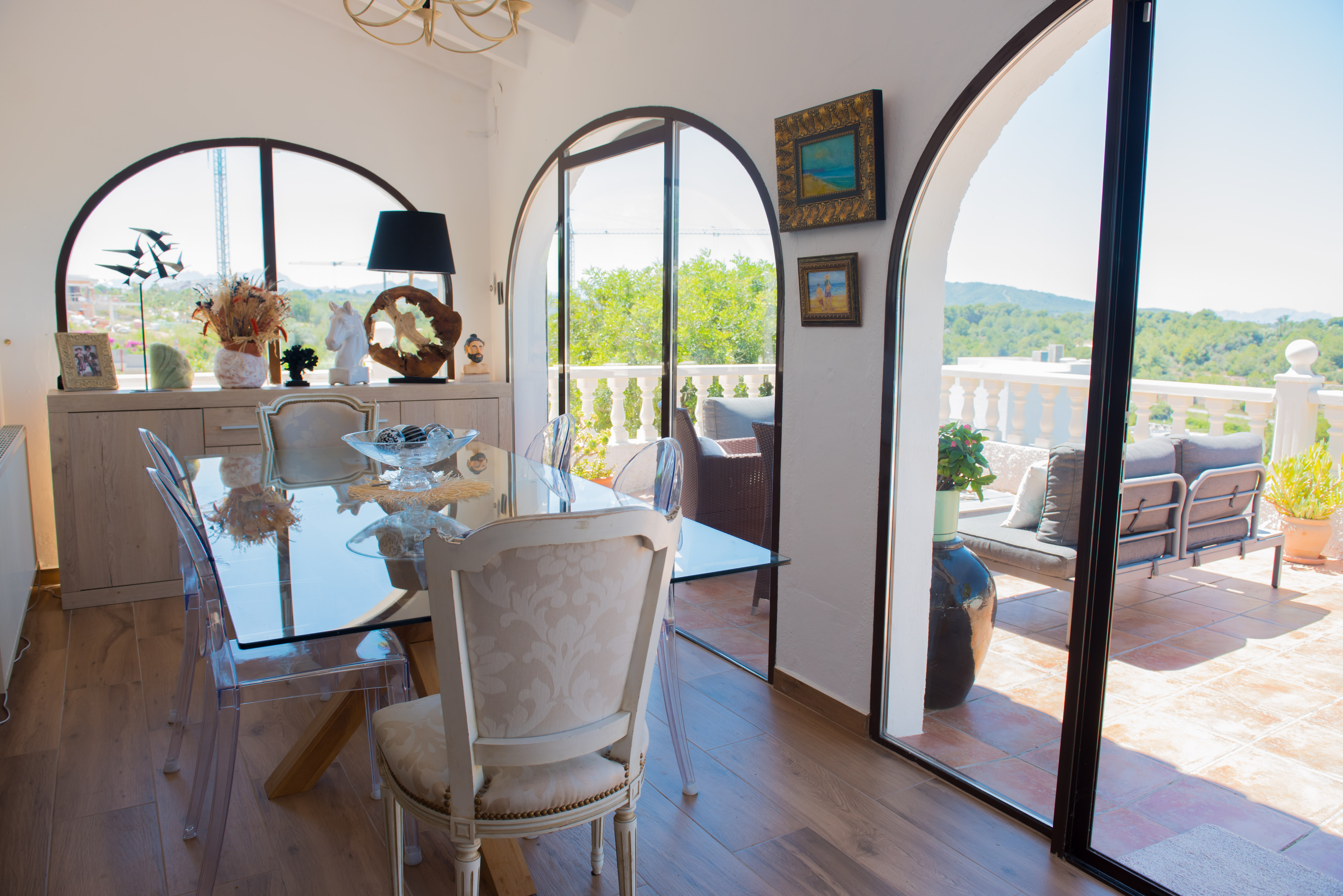 Lichte eetkamer met glazen tafel en toegang tot een terras met uitzicht op de bossen.