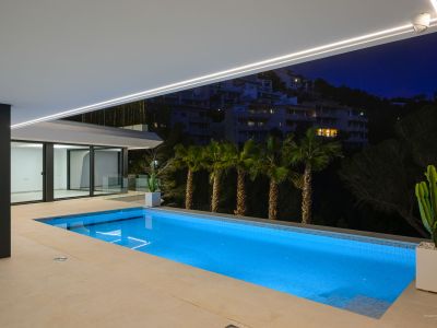 Moderne infinity pool met ruim zonneterras, met panoramisch uitzicht op de Middellandse Zee. De buitenruimte toont eigentijds design en weelderige, onderhoudsarme beplanting.
