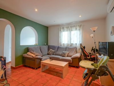 Ruime woonkamer met groene accentmuur en boogopeningen, terracotta tegelvloer en een comfortabele hoekbank. Functionele indeling met natuurlijk lichtinval.