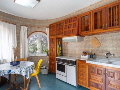 Functionele keuken met traditionele houten kasten, decoratieve wandtegels en een boograam. Een eethoek met ronde tafel profiteert van natuurlijk licht.
