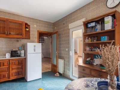 Keuken met blauwe vloertegels en wandtegels met patroon. Voorzien van houten kasten, een koelkast en directe toegang tot een buitenterras.