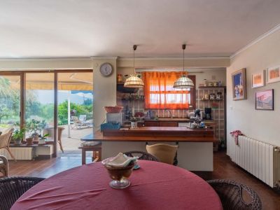 Open woon- en eetkamer met geïntegreerde keuken, houten bar en directe toegang tot het buitenterras via grote glazen schuifdeuren.