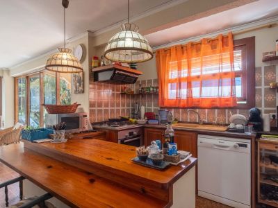 Rustieke keuken met houten bar, decoratieve tegels, geïntegreerde apparatuur en uitzicht op een aangrenzend glazen terras.