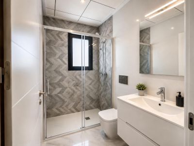 Moderne badkamer met inloopdouche, grijze geometrische tegels en raam. Witte wastafelmeubel, verlichte spiegel en marmerlook vloer.