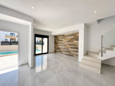 Ruime woonkamer met gepolijste porseleinen tegels, een decoratieve wand met houtlookpanelen en directe toegang tot het privézwembad. Moderne trap met glazen balustrade.