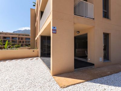 Exterieur van de begane grond met moderne okerkleurige gevel. Voorzien van een privétuin met wit grind en een overdekt terras met directe toegang, met uitzicht op de bergen.