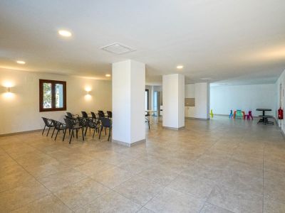 Ruim gemeenschappelijk sociaal centrum met tegelvloer, structurele pilaren en inbouwverlichting. Voorzien van een zithoek voor vergaderingen en een kleurrijke kinderhoek.