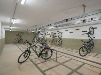Ruime gemeenschappelijke fietsenstalling met genummerde vloerplaatsen en wandrekken. Helder verlicht door tl-buizen, biedt het veilige opslag binnen het wooncomplex.